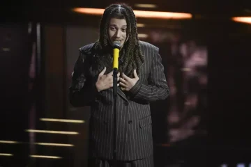 Sanremo 2026 – Sayf contailleur doppio petto rigato marrone, con cravatta di pelle.